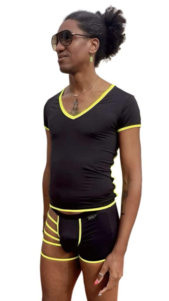 Mujer con ropa deportiva negra y detalles en amarillo, usando gafas de sol y accesorios, en un estil.