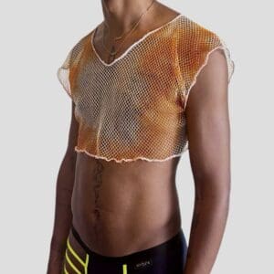 Jeune fille portant un haut en résille orange et un pantalon de survêtement noir, dans un style sportif.