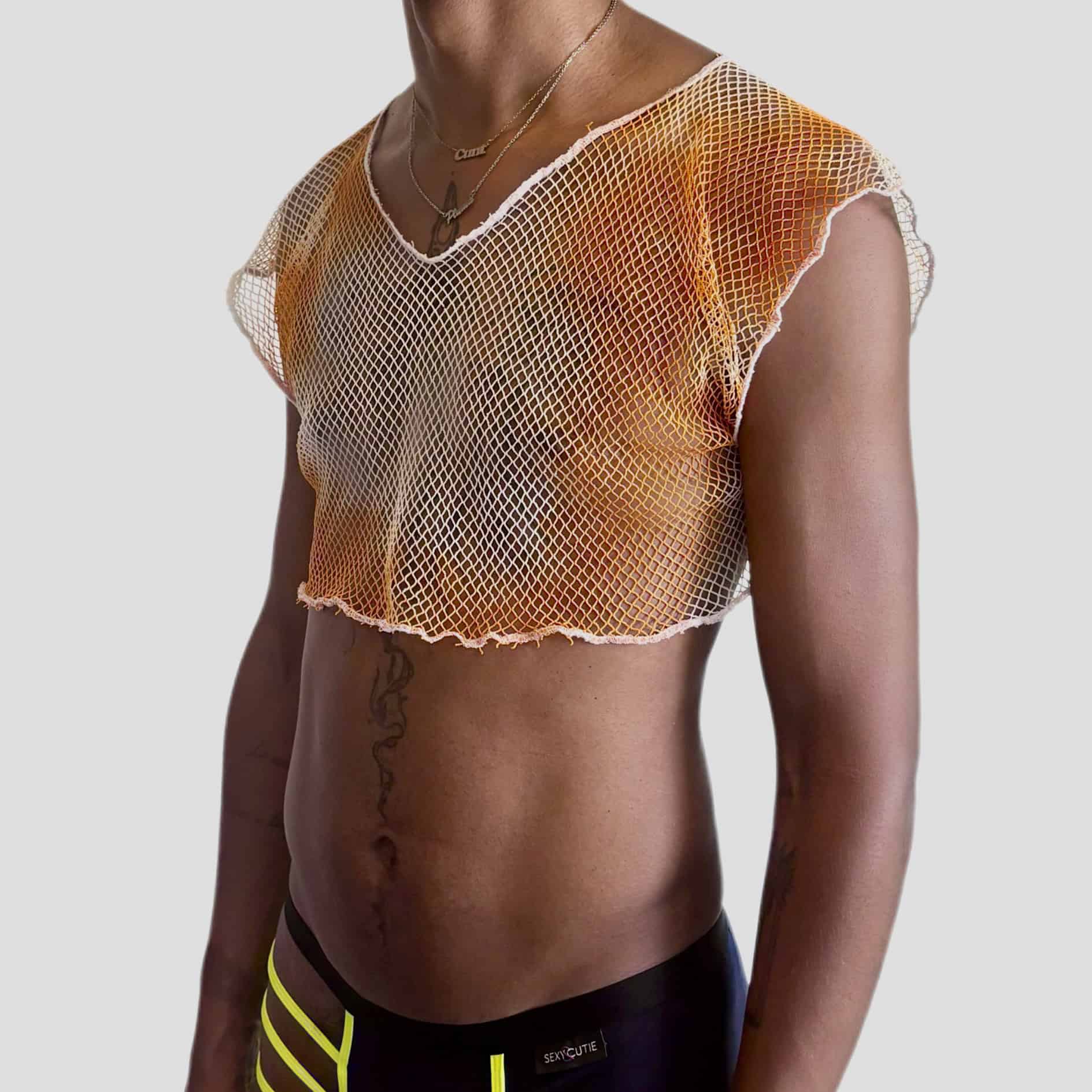 Jeune fille portant un haut en résille orange et un pantalon de survêtement noir, dans un style sportif.