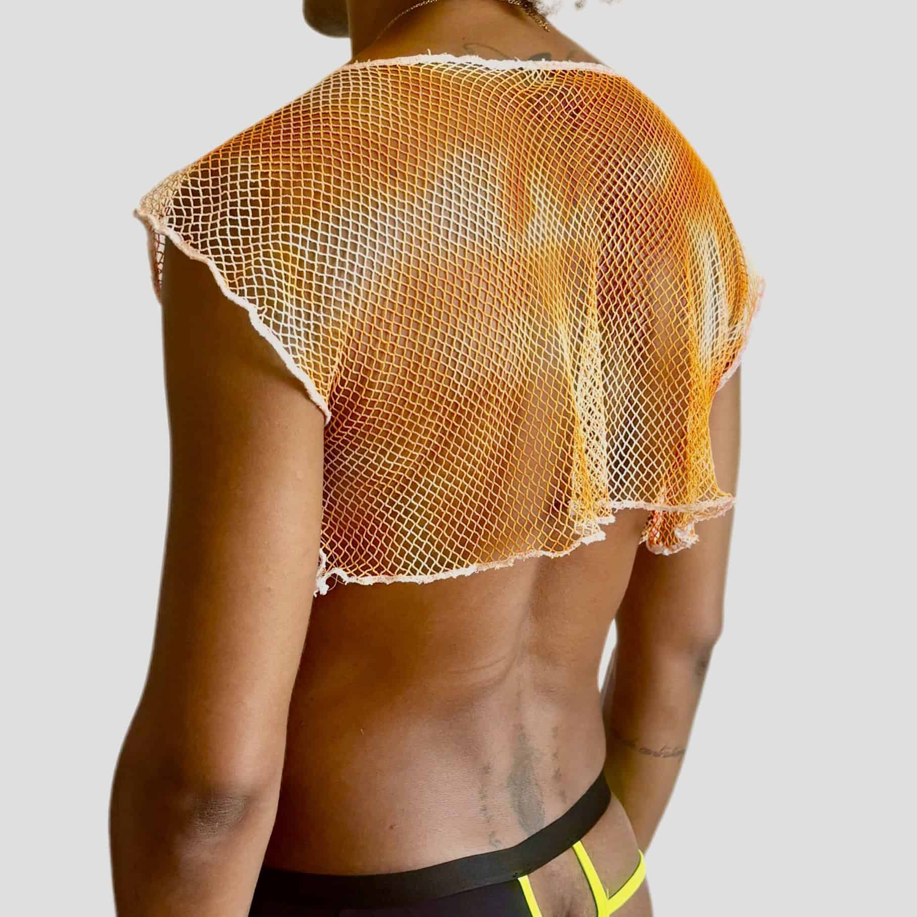 Femme portant un haut en résille orange et un short noir et jaune.