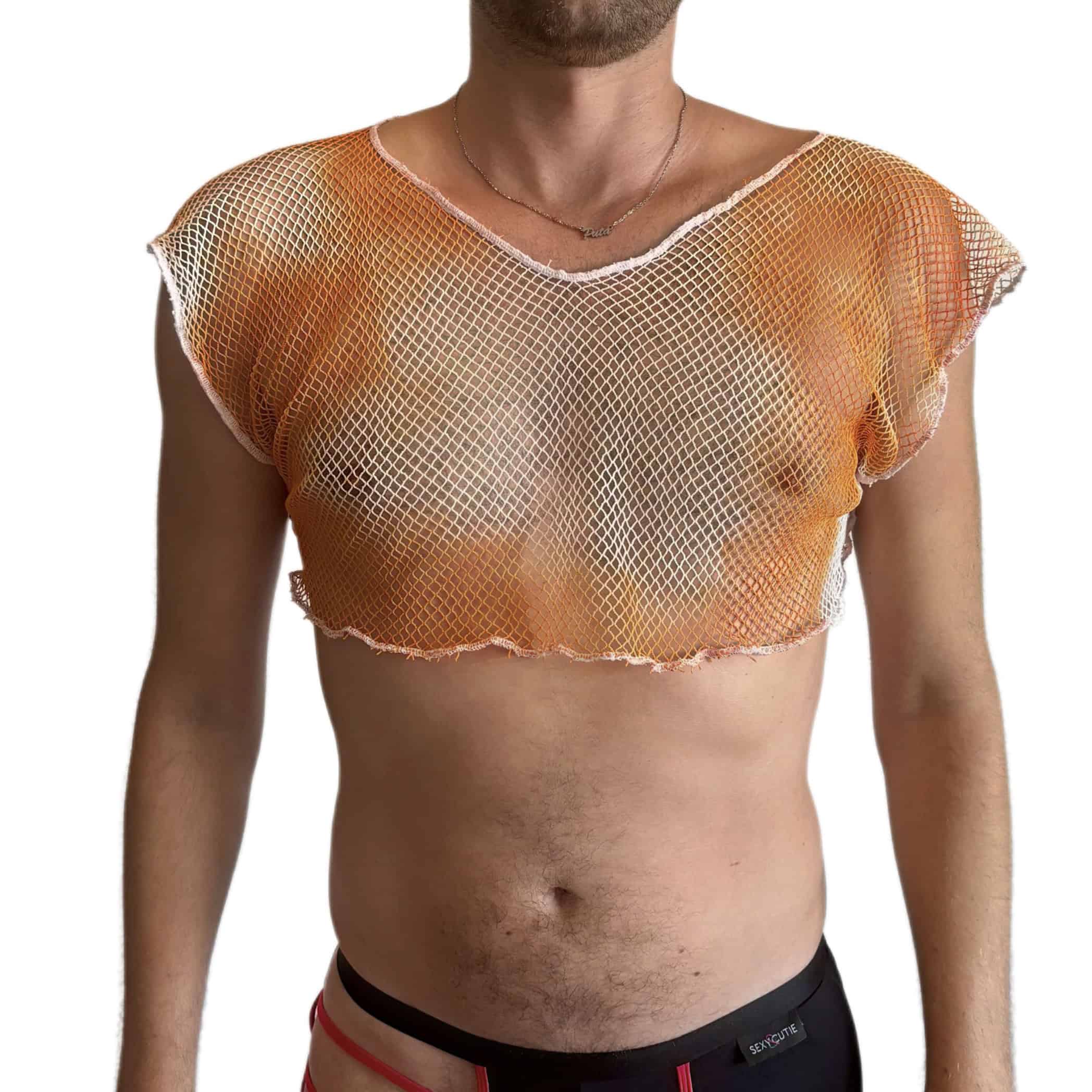 Garçon portant un crop top rose en résille et un pantalon noir sur fond blanc.