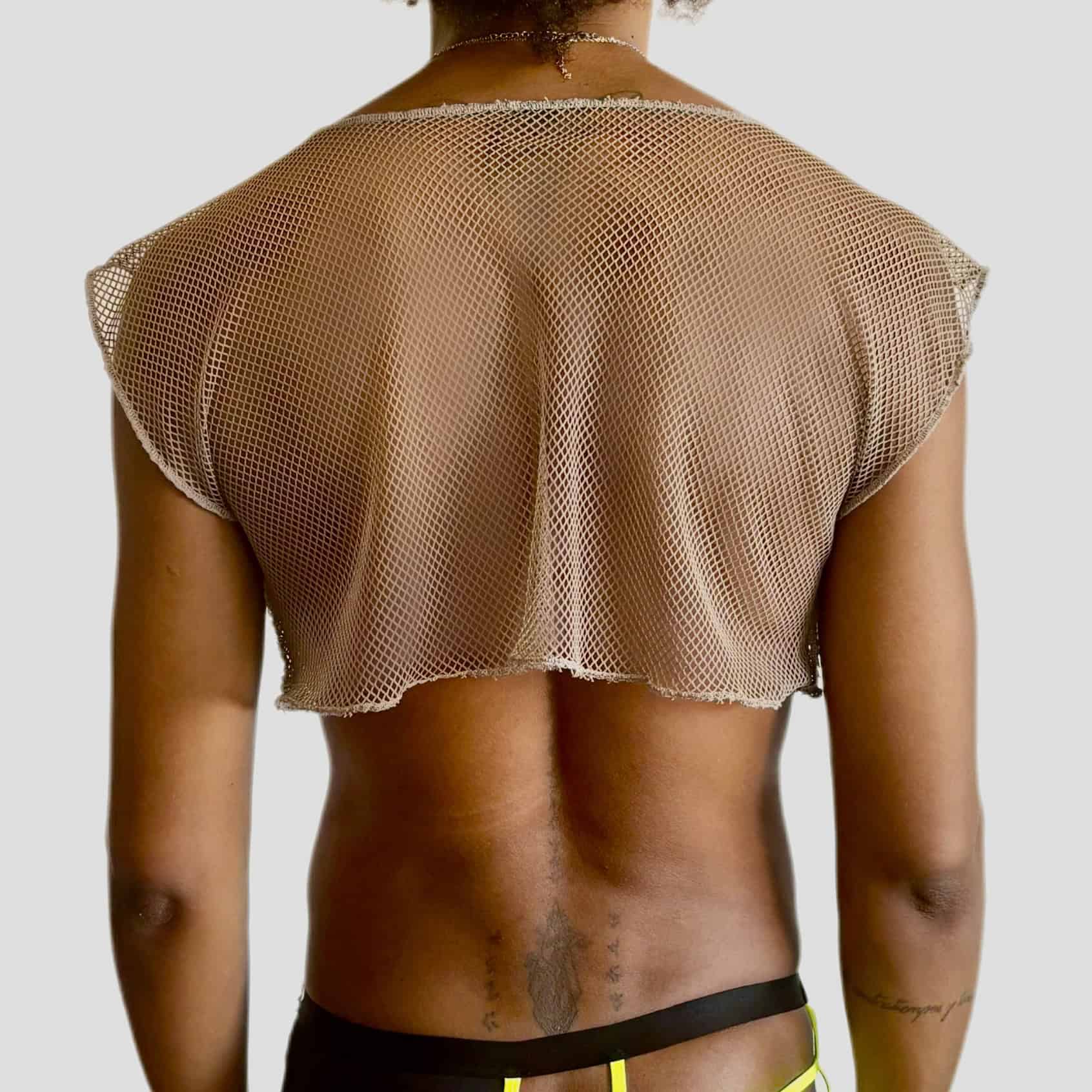 Femme portant un haut en résille rose et un short noir, vue de dos.